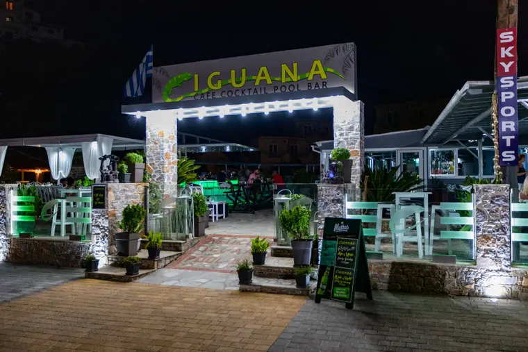 The entrance at night, lined with lights and plants