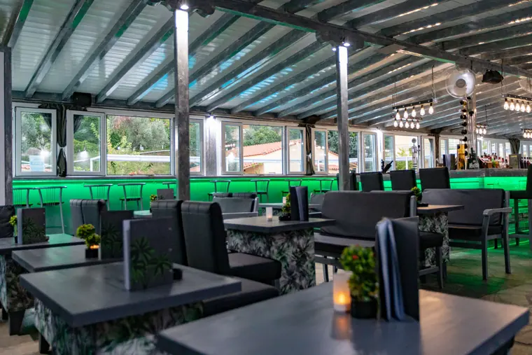 Tables along the green-lit terrace